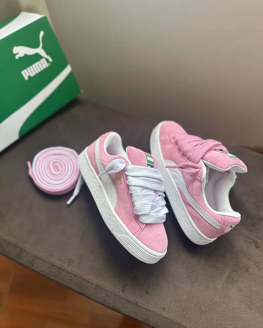 Puma Suede XL pink suede sneakers with thick white fat laces, white Formstrip, and a green Puma shoe box.